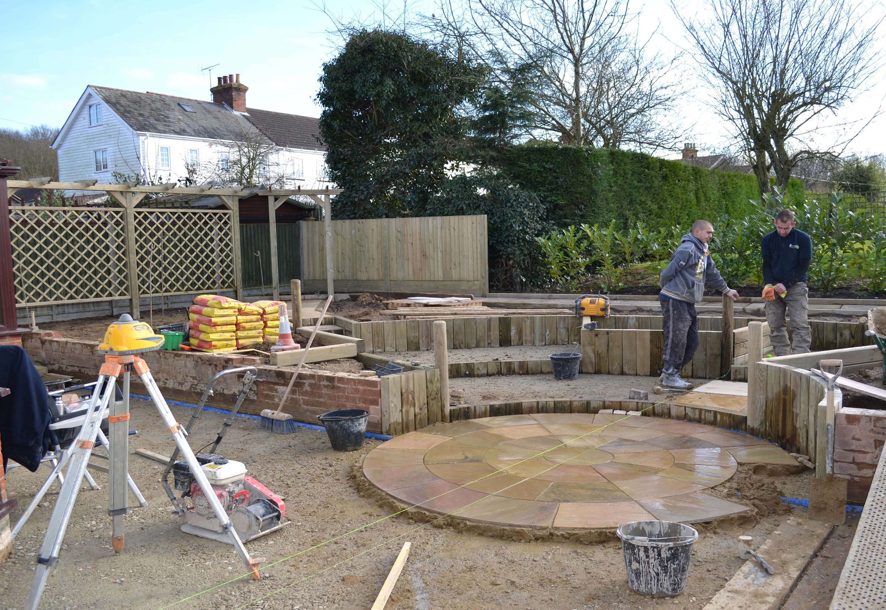 Building the central paving feature with trellis and fencing in the background